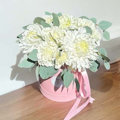 White chrysanthemum bouquet in a pink hatbox with a ribbon