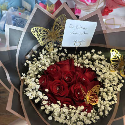 Red roses with white baby's breath in black wrap and butterfly accents