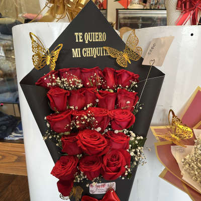 Red roses in a black cone wrap with a red ribbon and gold butterfly accents