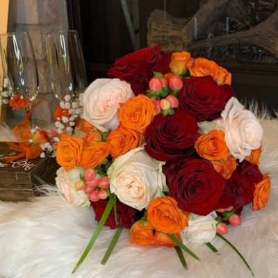 Bouquet of red, orange, and white roses with small berry accents