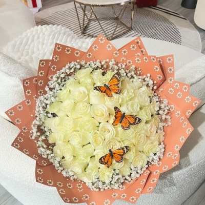 Bouquet of pale yellow roses with butterfly accents and peach wrapping