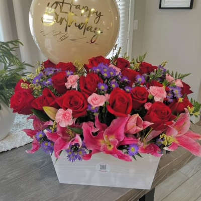 Red roses and pink lilies in a white box with a birthday balloon