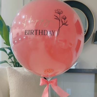 Pink birthday balloon with a ribbon and chocolates below
