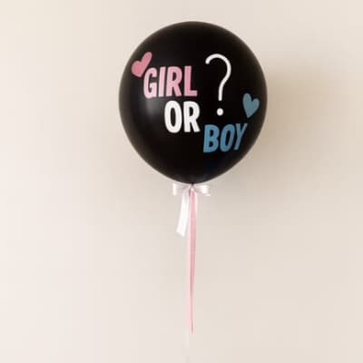 Black gender reveal balloon with pink and blue text, tied to a cluster of blue and pink balloons