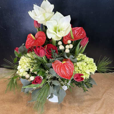 Red and white floral arrangement with tulips, anthuriums, and lilies in a white vase