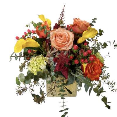 Mixed bouquet with peach roses, yellow calla lilies, and greenery in a square vase