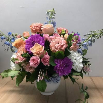Mixed pink, purple, and blue flowers in a white vase