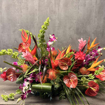 Tropical floral arrangement with orange heliconia, red anthuriums, and purple orchids