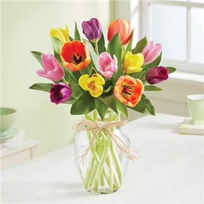 Mixed-color tulip bouquet in a clear glass vase tied with raffia