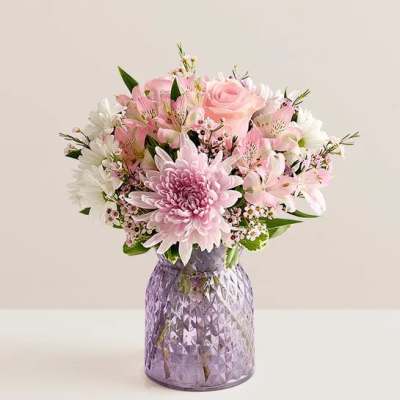 Pink and white mixed flower arrangement with roses and mums in a textured lavender glass vase