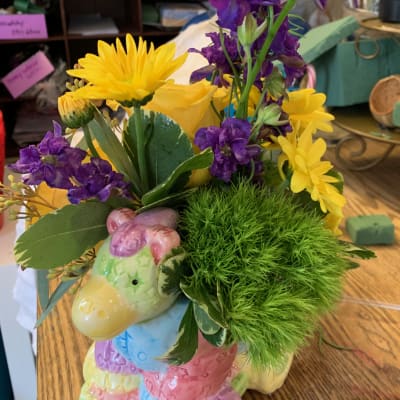 Yellow and purple flowers arranged in a pastel ceramic animal planter