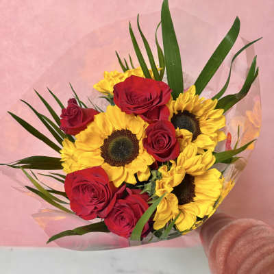 Bouquet of red roses and yellow sunflowers wrapped in pink paper