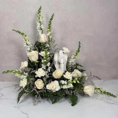 White floral arrangement with roses, snapdragons, and an angel figurine