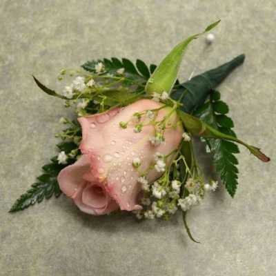Pink calla lily corsage with small white flowers and greenery