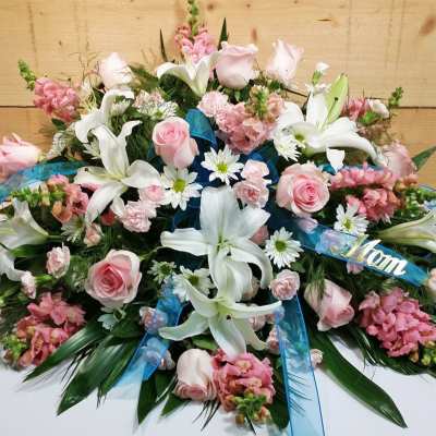 Pink and white floral arrangement with lilies and roses, accented by blue ribbon