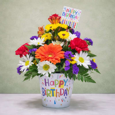 Colorful mixed flower arrangement in a birthday pot with a card