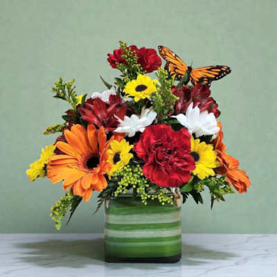 Mixed bouquet of orange, red, yellow, and white flowers in a green striped vase