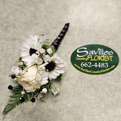 White floral boutonniere with daisies and a rose on a gray surface