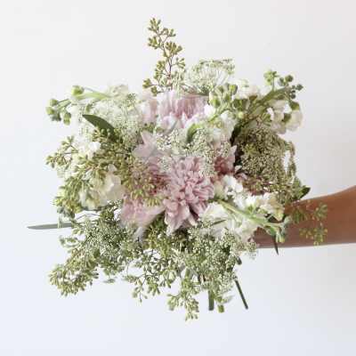 Handheld bouquet of pale pink and white flowers with airy greenery