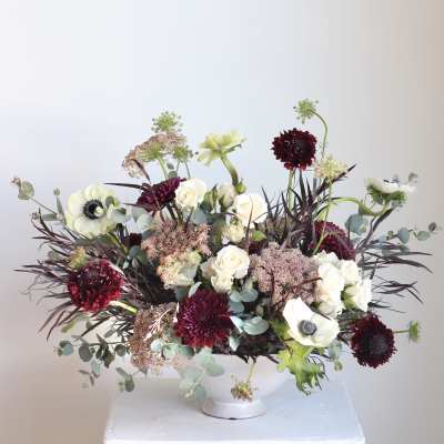 Mixed bouquet of white and burgundy flowers in a white vase