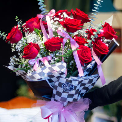 Bouquet of red roses with pink ribbons and checkered wrap
