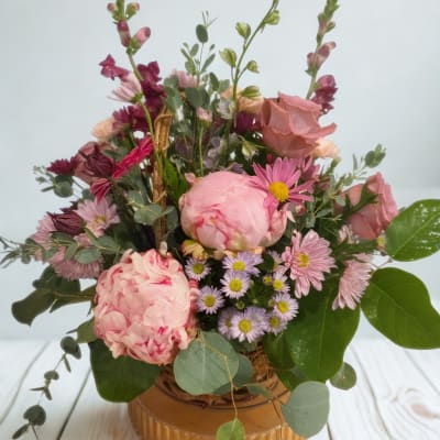 Mixed pink floral arrangement in a low round container