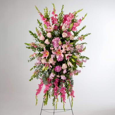 Tall pink and white standing spray with lilies, roses, and hydrangeas on an easel.
