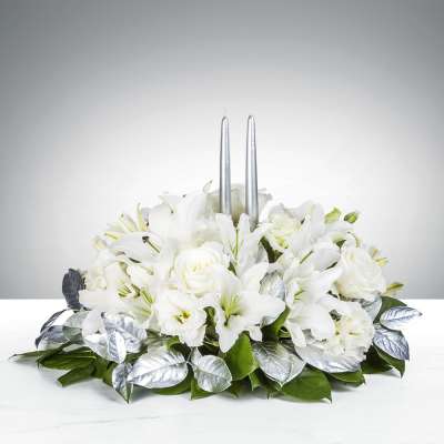 Low white arrangement of lilies and roses with silver candles and silver-toned leaves