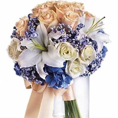 Bouquet of cream roses, white lilies, and blue flowers in a glass vase