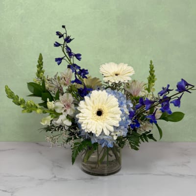 Blue and white flower arrangement in a clear glass vase