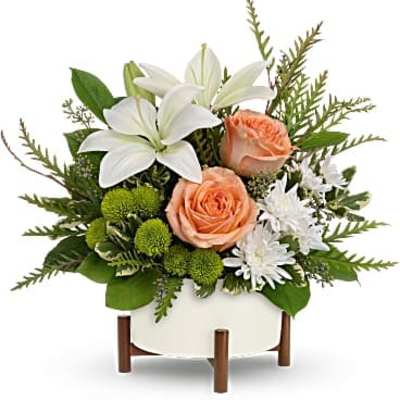 White lilies and peach roses in a white vase with greenery