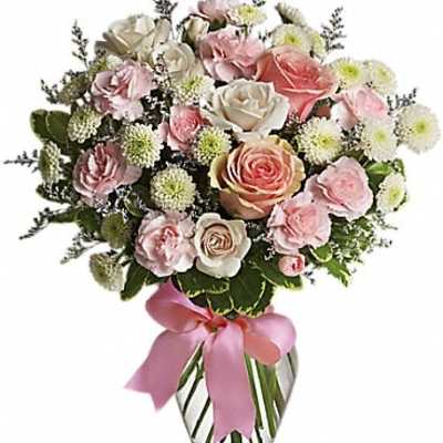 Pink and white rose bouquet in a clear glass vase with a pink ribbon