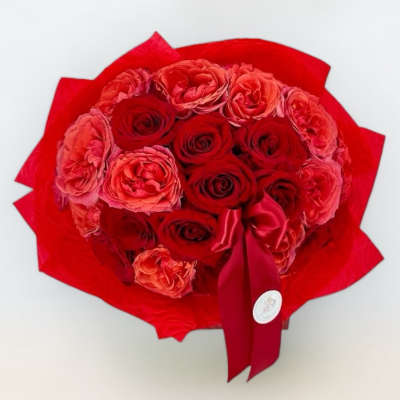Red rose bouquet wrapped in bright red paper with a satin ribbon