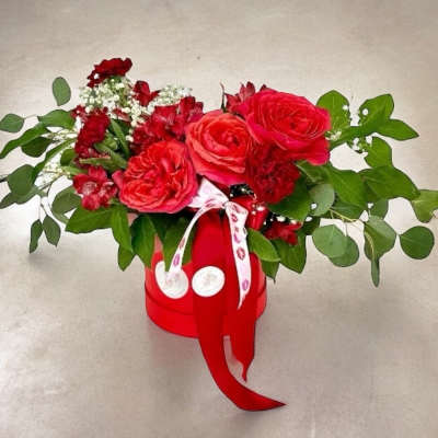 Red rose bouquet in a red hatbox with ribbon