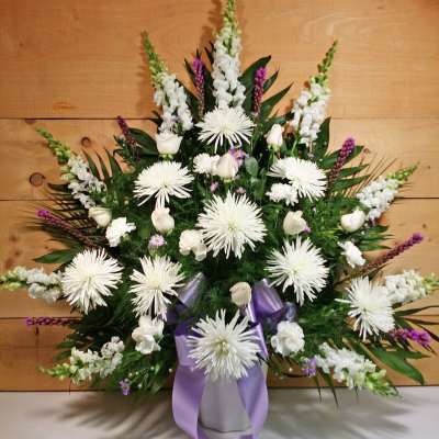 White floral standing spray with purple ribbon accents