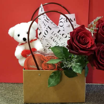 Gift box with red roses, a teddy bear, and a Valentine card