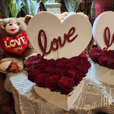 Heart-shaped rose arrangements with "love" signs and teddy bears