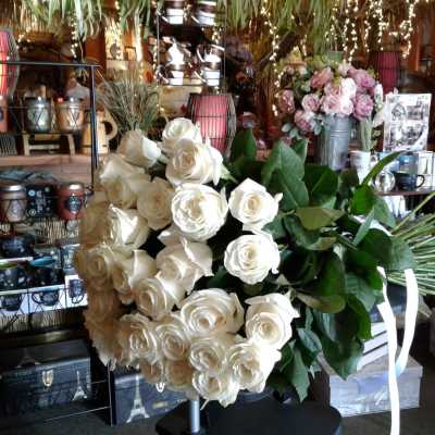 Large bouquet of white roses with green leaves and white ribbon