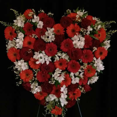 Heart-shaped floral arrangement with red and white flowers on a stand