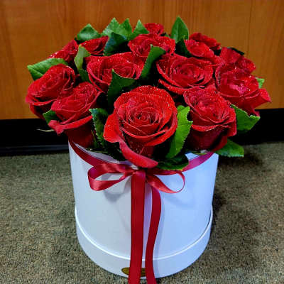 Red roses arranged in a white round box with a red ribbon