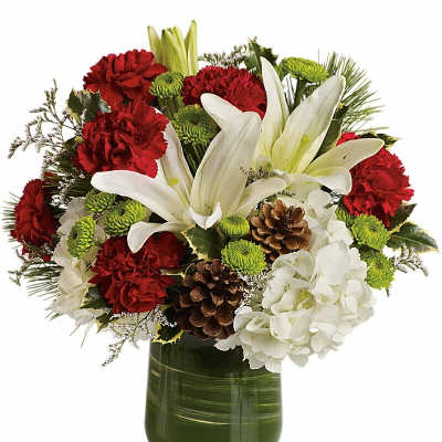 Red carnations and white lilies in a green glass vase with pinecones