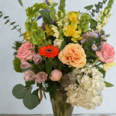 Mixed bouquet in a glass vase with roses, lilies, and hydrangeas