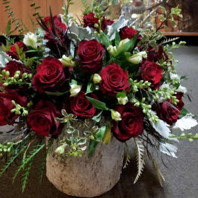 Red rose arrangement in a rustic white vase