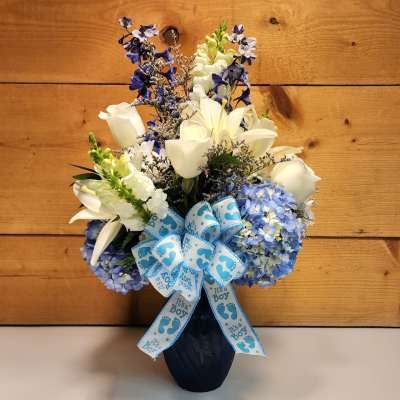 Blue and white flower arrangement in a vase with an "It's a Boy" ribbon