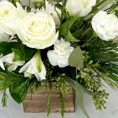 White roses and lilies in a wooden box with greenery