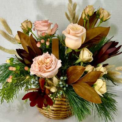 Basket arrangement of pale pink roses with dried grasses and greenery