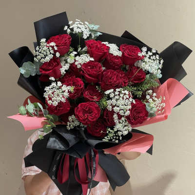 Bouquet of red roses with white filler flowers and black-and-pink wrapping