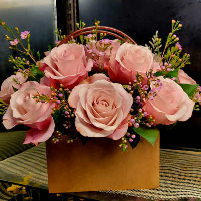 Pink roses arranged in a brown box with small purple filler flowers