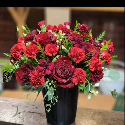 Red roses and carnations arranged in a black vase