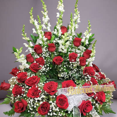 Red roses with white snapdragons and baby's breath in a large arrangement.